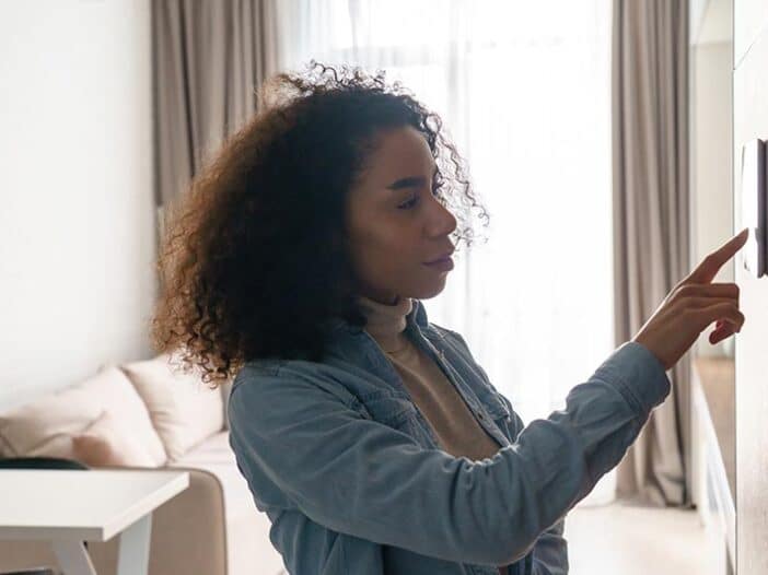 5 Signs You Might Need A New Hvac Thermostat | Solace Plumbing, Heating, And Air A Person With Curly Hair Is Adjusting A New Smart Thermostat On A Living Room Wall, Seamlessly Integrating Efficient Hvac Technology Into Their Home.