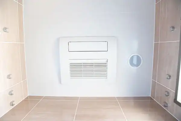 The bathroom ceiling features a white ventilation panel, complementing the beige tiles on the walls and four small metal knobs arranged symmetrically. This installation is perfect for enhancing air circulation, much like a dehumidifier would in humid Nashville climates.