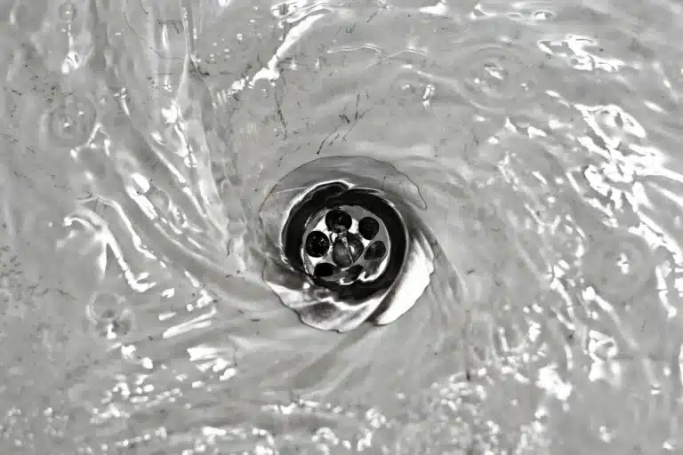 Water elegantly swirling down a silver sink drain in Jackson, TN.