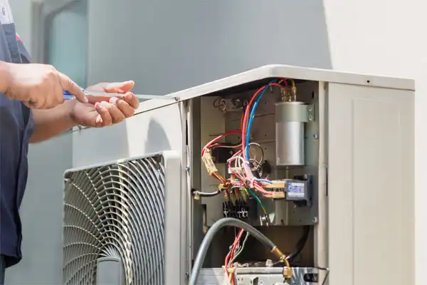 In Nashville, a technician is expertly repairing an outdoor air conditioning unit, carefully navigating the exposed wires and components.