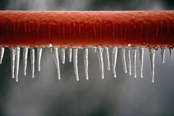A red pipe with icicles hanging from it stands out against a blurred backdrop, highlighting the need for frozen pipe repair in Jackson, TN.